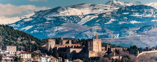 Winter view of famous Alhambra in front of Sierra Nevada mountains topped with show.